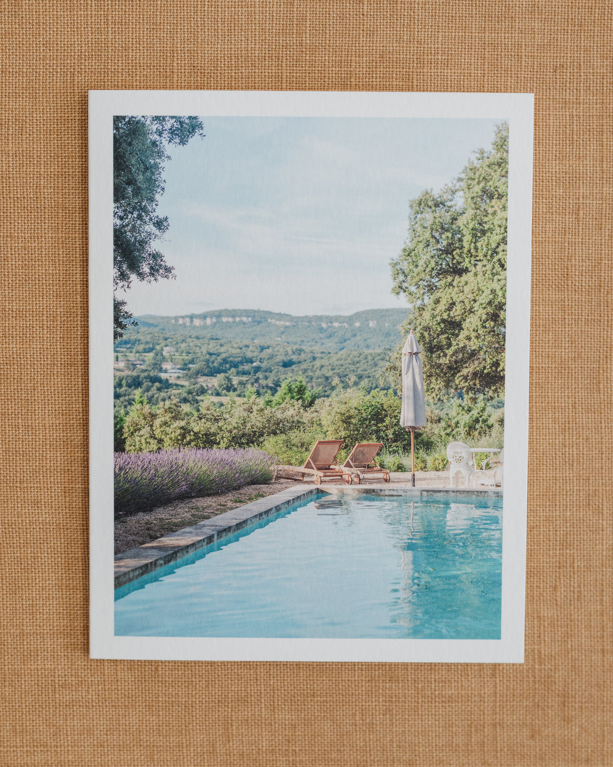 Photographic notecard showing a turquoise pool, lounge chairs, and green hills in Provence.