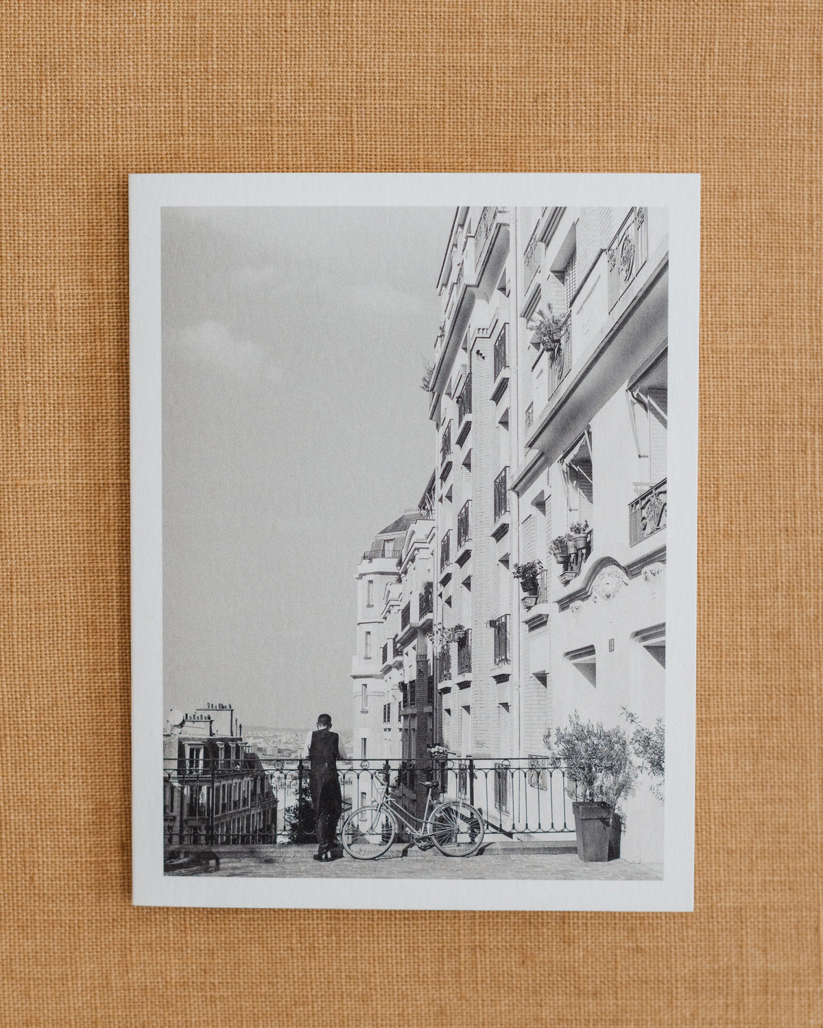 Black-and-white photographic notecard showing a French waiter beside a bicycle in Paris.