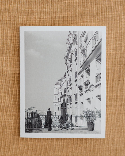 Black-and-white photographic notecard showing a French waiter beside a bicycle in Paris.